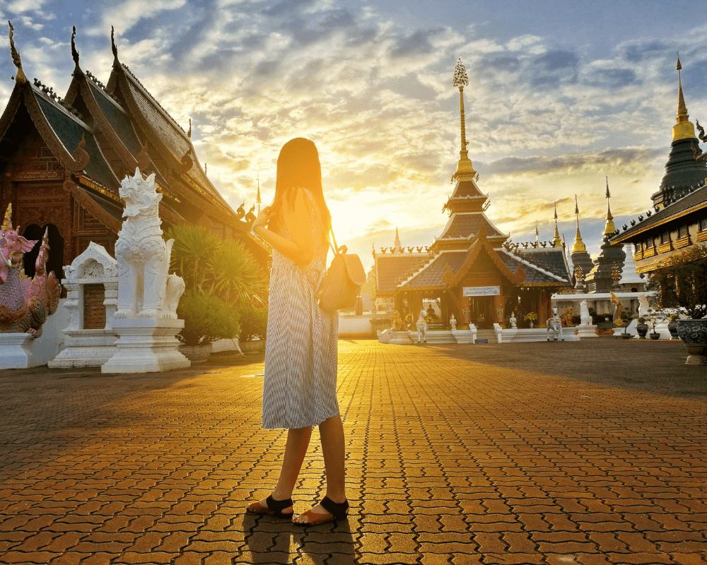 A picture of a woman standing in front of temples in Chiang Mai