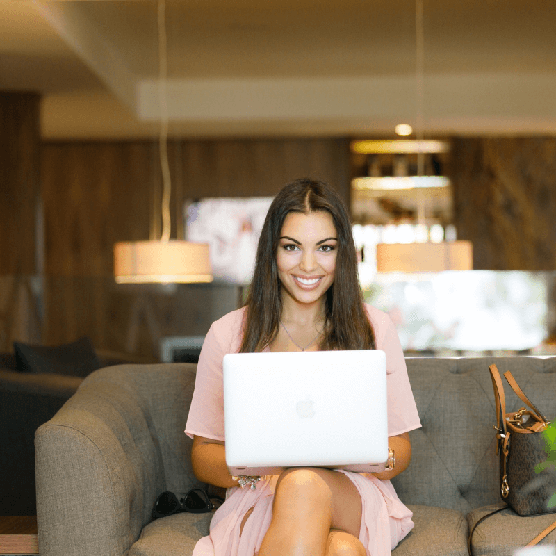 Women sitting on couch with a laptop smiling.