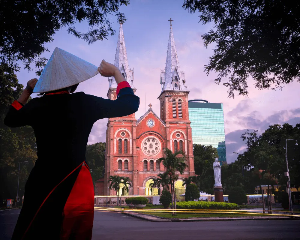 A woman in traditional dress outside the Notre Dame Cathedral Of Saigon