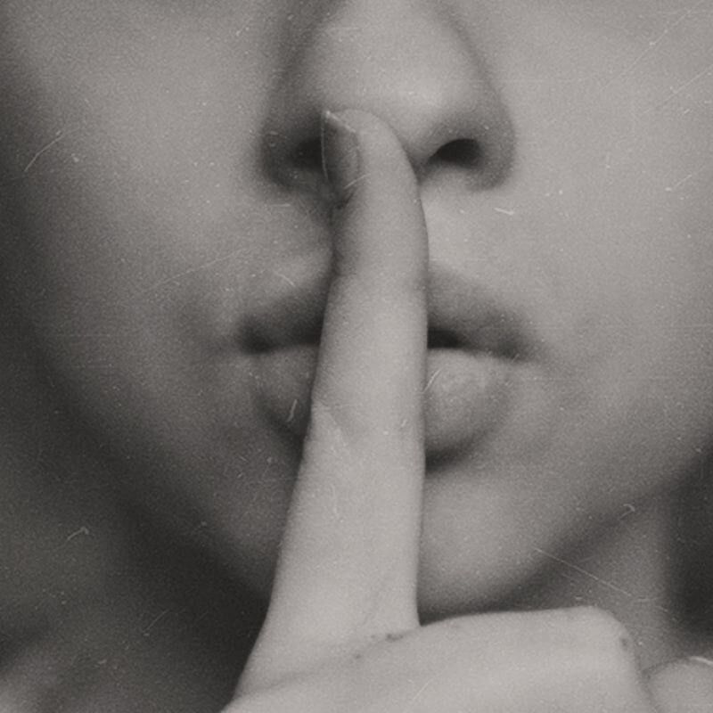A woman holding her finger to her mouth to be quiet