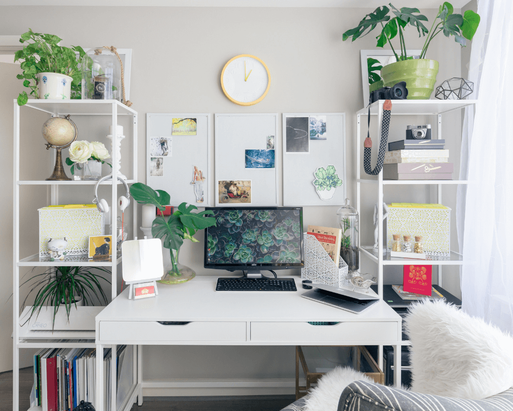 An office decorated with shelves on either side of desk with green and white accessories