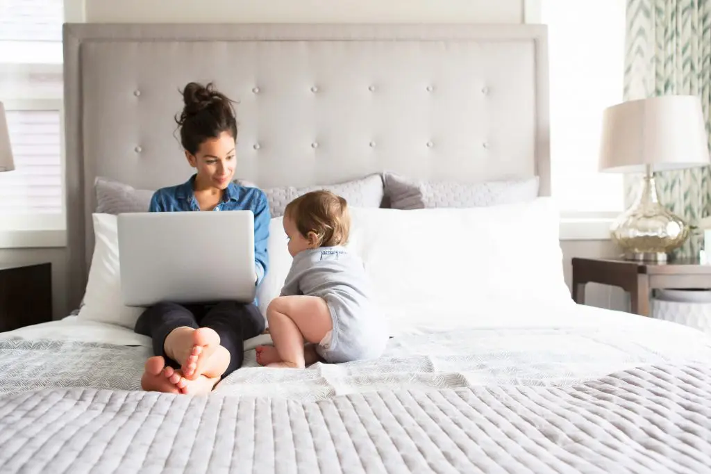 mom working on laptop baby bed