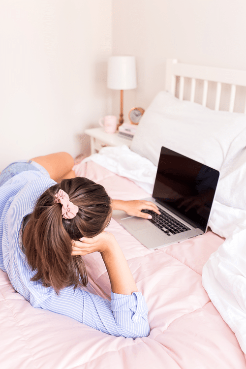 Woman working on laptop on the bed
