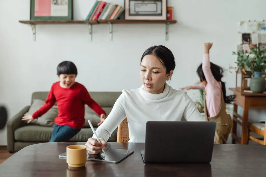 mom working with kids playing in background