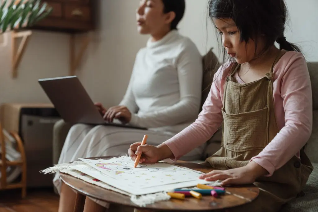 mom working on computer while kid draws