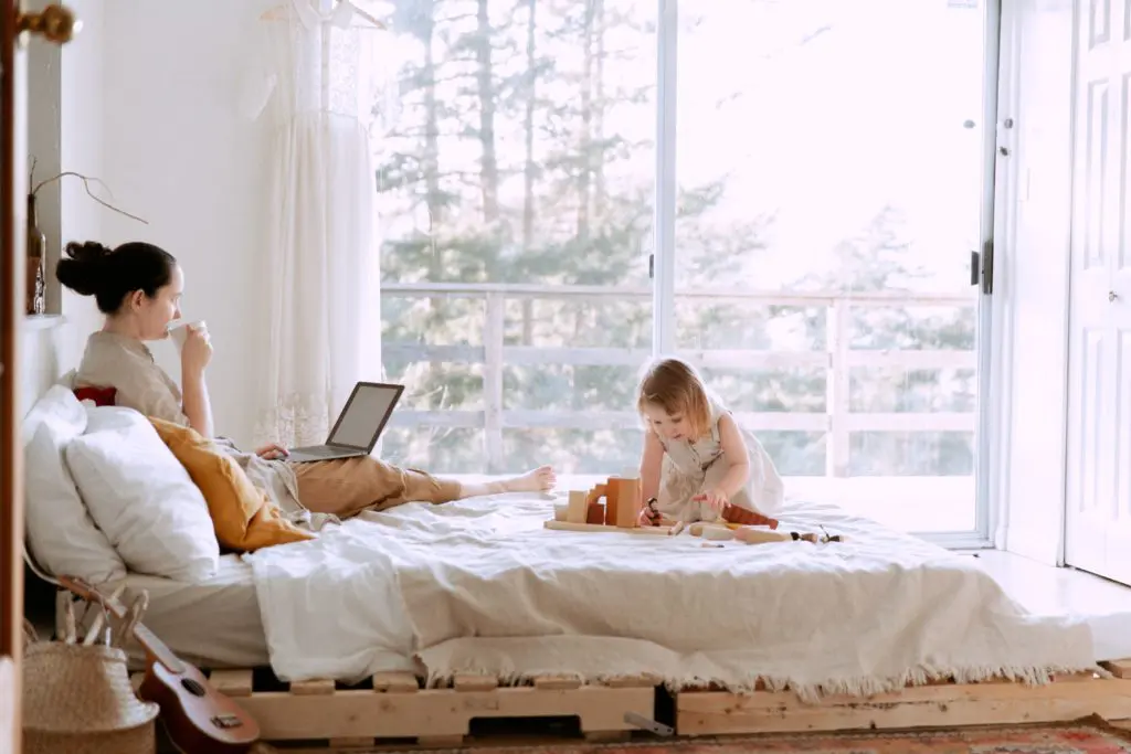 mom working from home with child on bed