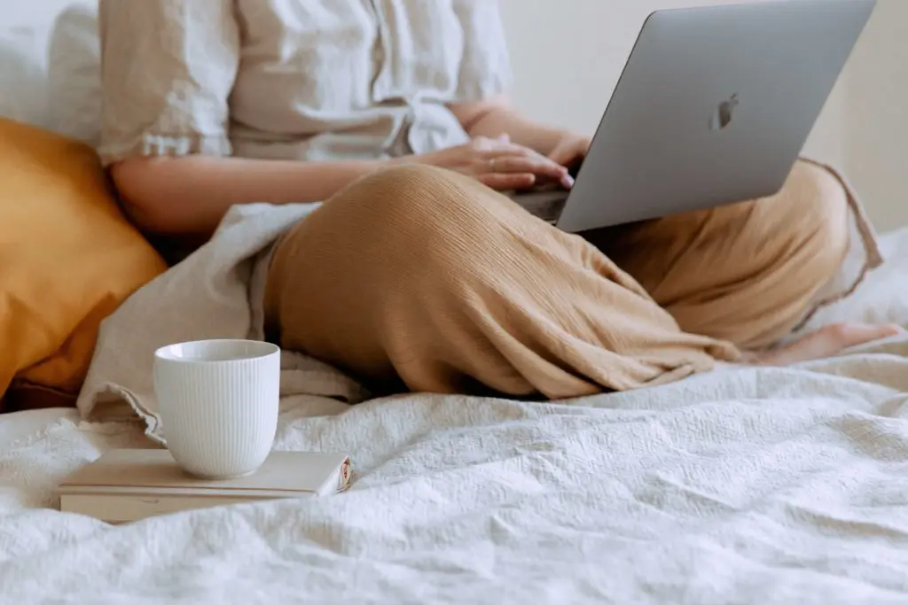 girl sitting on bed working from home on laptop