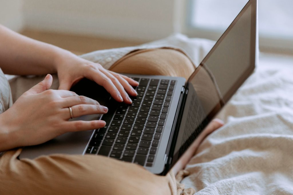 woman working on laptop on bed