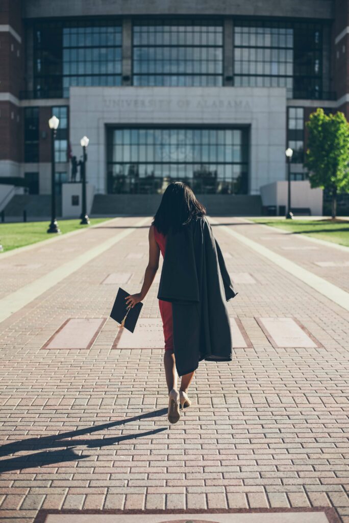 woman graduating college walking away with cap in hand and gown