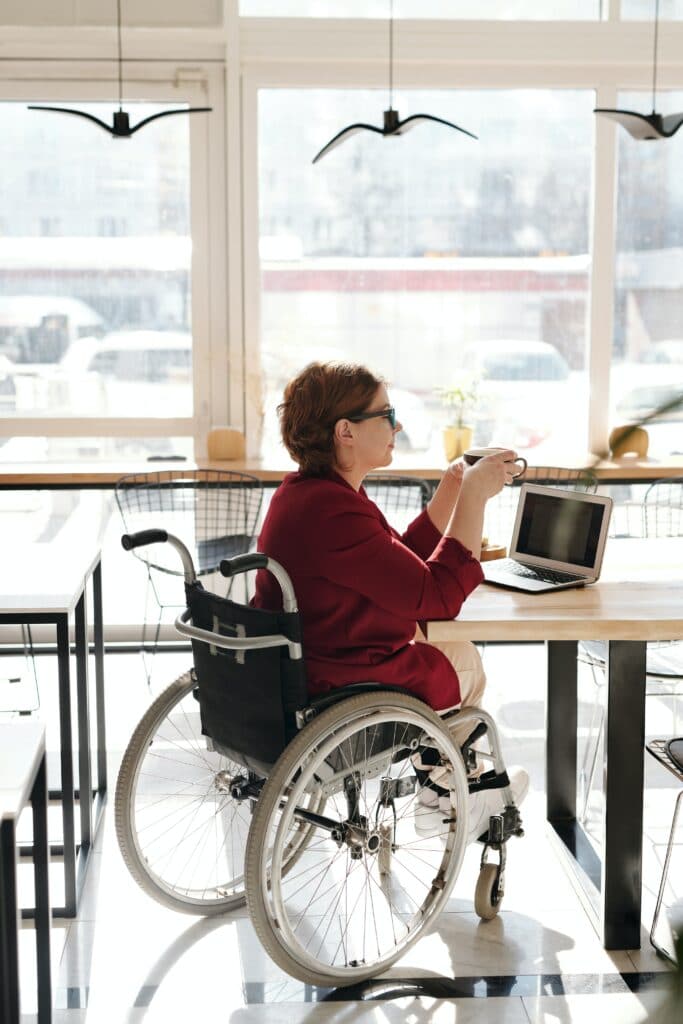 virtual assistant in wheelchair working remotely in cafe with disability
